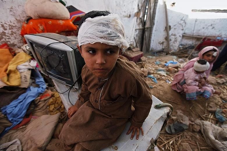 A Pakistani boy who was injured in the earthquake on Monday sitting in his damaged home in Peshawar, Pakistan.