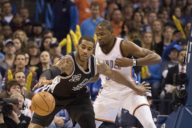 San Antonio's LaMarcus Aldridge (No. 12) being guarded closely by Oklahoma's Kevin Durant. Aldridge, in his first game since moving from the Portland Trail Blazers, was held to 11 points, while Durant notched 22 points.