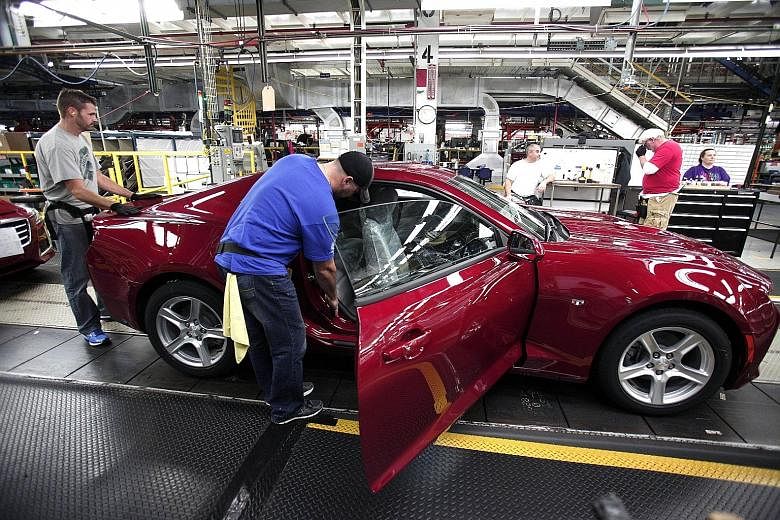 Workers on Monday putting finishing touches to a new General Motors 2016 Chevrolet Camaro at GM's assembly plant in Lansing, Michigan. Investors are now waiting for third-quarter US GDP and non-farm payroll data on Nov 6 to see if there is a case for