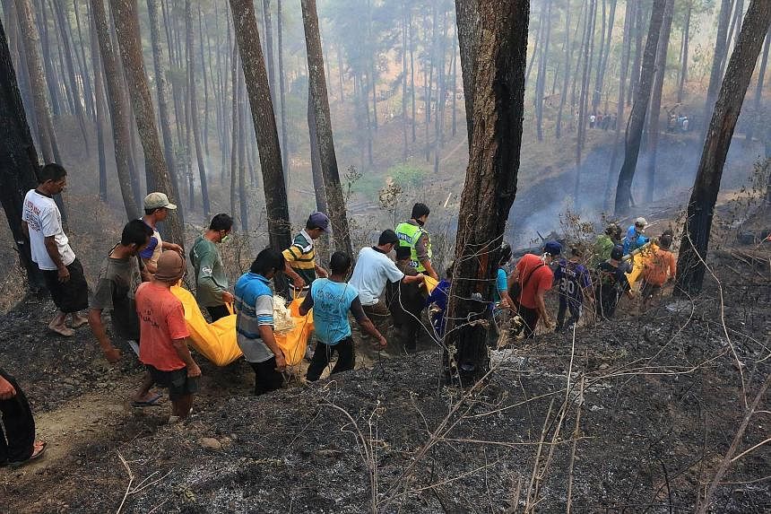 Indonesian villagers carrying the bodies of four people who were killed while trying to put out a forest fire in Ponorogo district in East Java on Thursday.