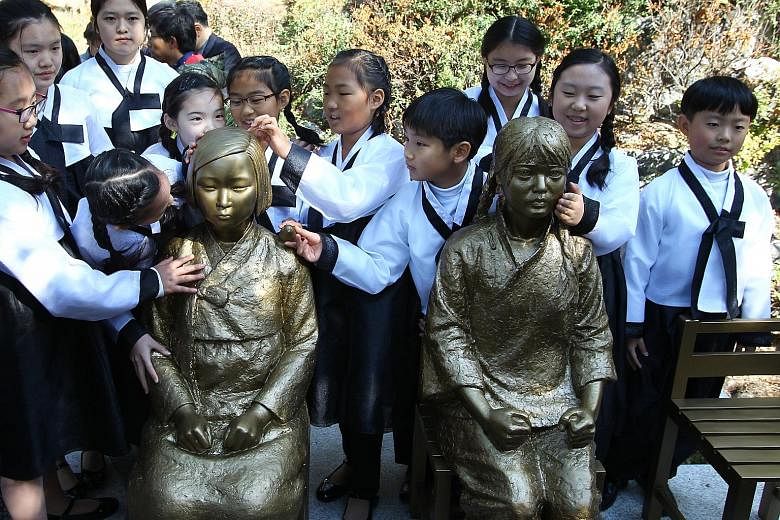 Schoolchildren crowding around bronze statues depicting Korean and Chinese "comfort women", who were forced into prostitution at Japanese wartime brothels, at a park in Seoul this week.