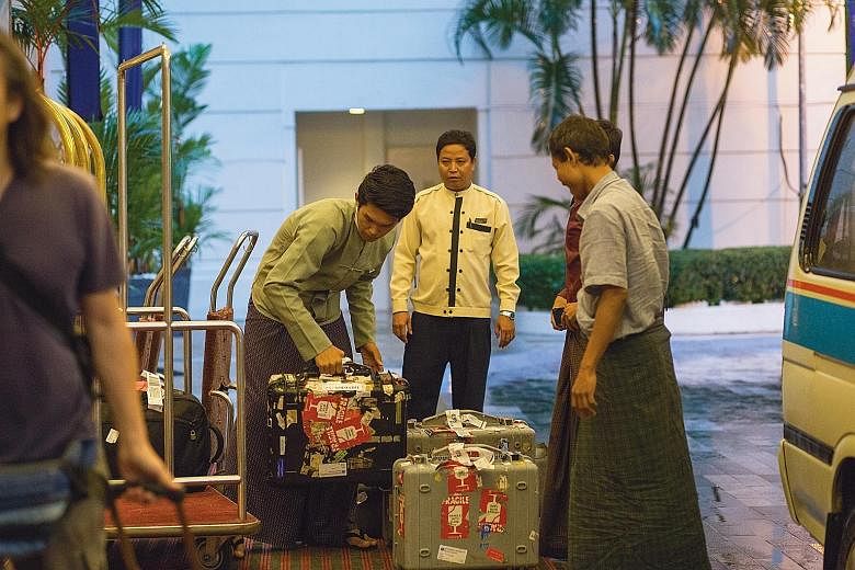 Security officer Myo Min (centre), 35, watching bellboy Wai Yan Tun (left), 21, transfer luggage at the Parkroyal Yangon.