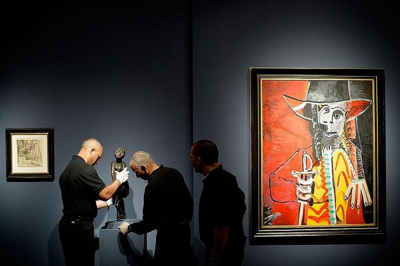 Workers making adjustments to the display of a sculptureduring a preview of an impressionist and modern art auction at Christie's in New York, on Friday. The auction house is expecting millions in sales.