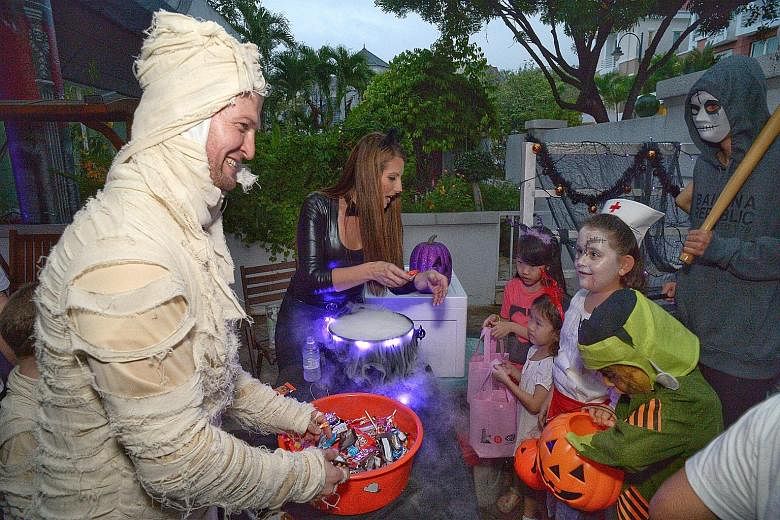 The rain failed to dampen the spirits of these children at Woodgrove last night. Many residents like Mr Jonathan Cabrera (right, in mummy costume), 36, and his wife Jennifer (dressed as Catwoman), 35, gave out treats.