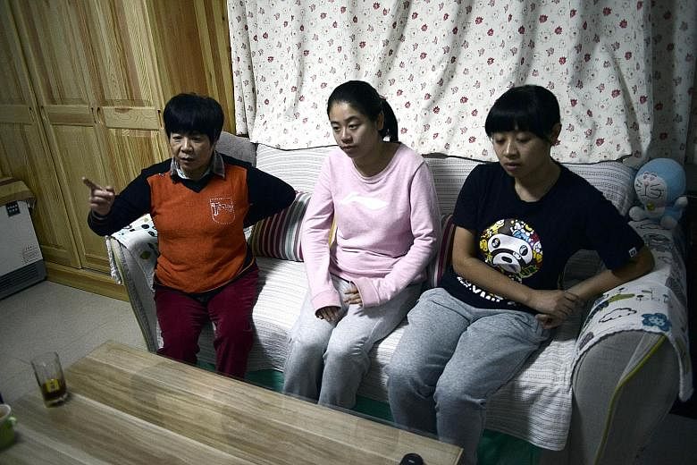 Ms Li Xue (left, centre) with her mother and older sister in their Beijing home. Born in violation of China's one-child policy, she has no right to schooling, healthcare or a formal job. Without a birth certificate or identity papers, she is unable t