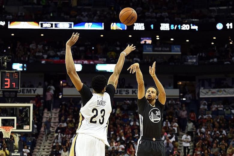 Stephen Curry (right) of the Golden State Warriors takes a three-point shot over Anthony Davis of the New Orleans Pelicans on Saturday. Curry's fluent 53 points in the game led the undefeated Warriors to a 134-120 win.
