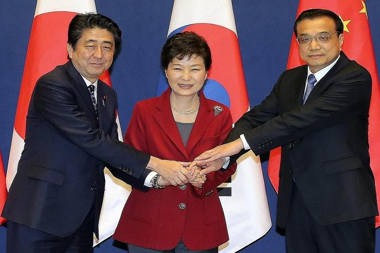 South Korean President Park Geun Hye (centre), Japanese Prime Minister Shinzo Abe (left) and Chinese Premier Li Keqiang at Cheong Wa Dae, the presidential office in Seoul, yesterday.