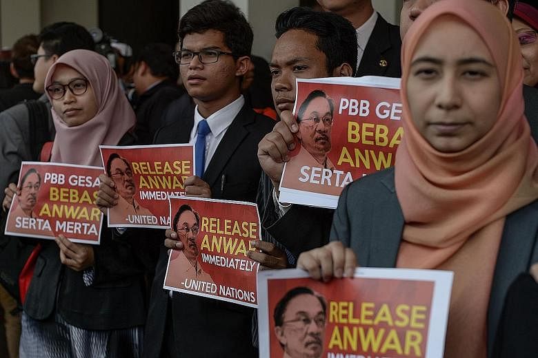Malaysian opposition members displaying placards that say "Release Anwar immediately" after a press conference on the UN body's opinion on Anwar Ibrahim at Parliament House in Kuala Lumpur yesterday.