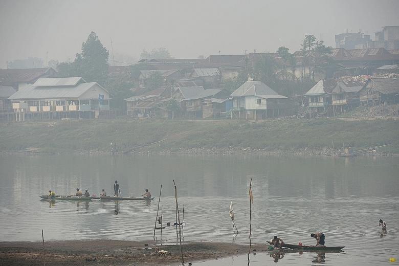 Fishing boats sail in a river shrouded in haze in the village of Serijabo in South Sumatra. For decades, many companies have adopted destructive practices, such as illegally grabbing lands and clearing the forests, thus setting Indonesia up for massi