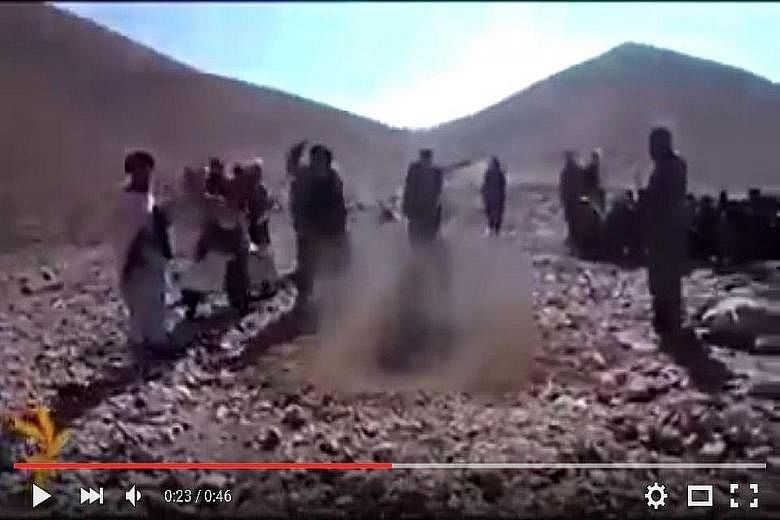 A screengrab from the graphic video showing the victim in a hole in the ground surrounded by men hurling stones at her.