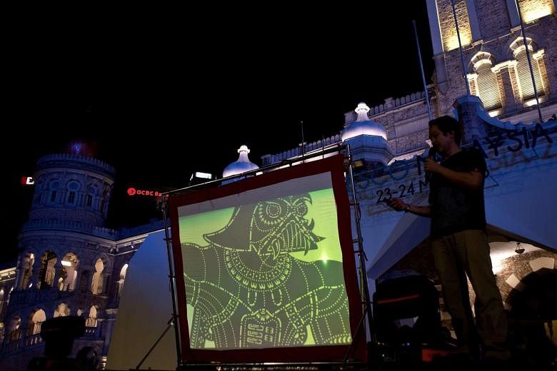 A distinctively Darth Vader-looking silhouette is projected on a screen as designer Chuo Yuan Ping, part of the team behind the Star Wars-inspired wayang kulit production, addresses the audience before a show at Independence Square in Kuala Lumpur.