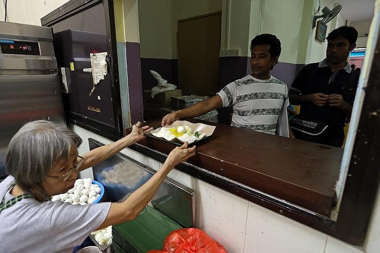 South Asian migrant workers collecting their free meals from the kitchen at Isthana Restaurant in Rowell Road, under a project by TWC2.