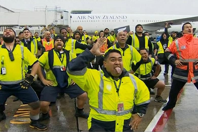 From far left: Auckland airport workers honouring the All Blacks with a Maori war dance, or haka, on the tarmac in heavy rain yesterday. All Blacks captain Richie McCaw holding the Webb Ellis Cup during a victory parade at Victoria Park.