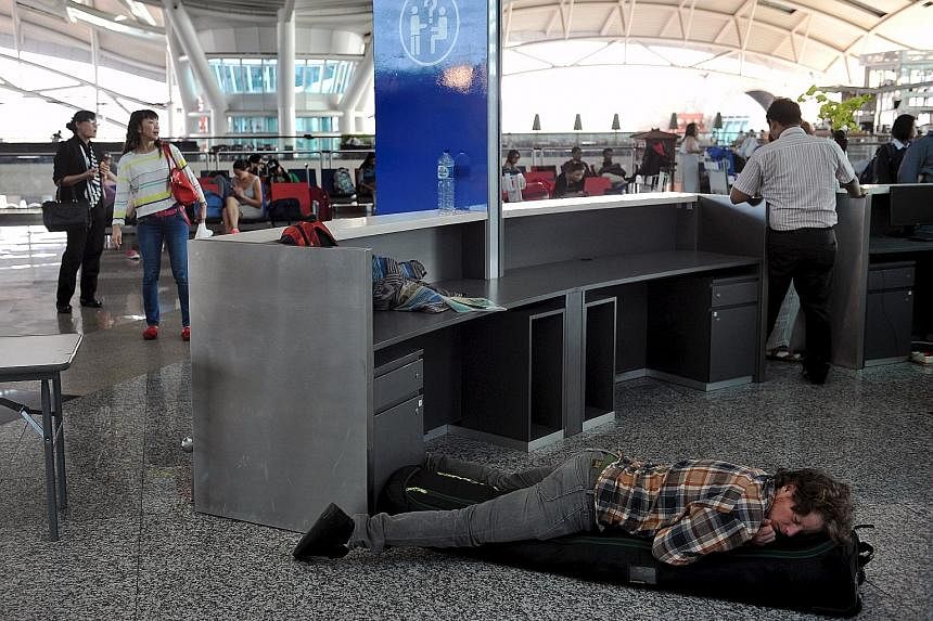A traveller catching some shut-eye yesterday at Bali's Ngurah Rai airport in this picture from Antara Foto. Nearly 700 flights have been cancelled, said the Bali airport authorities, because of a large ash cloud from Mount Rinjani on nearby Lombok is