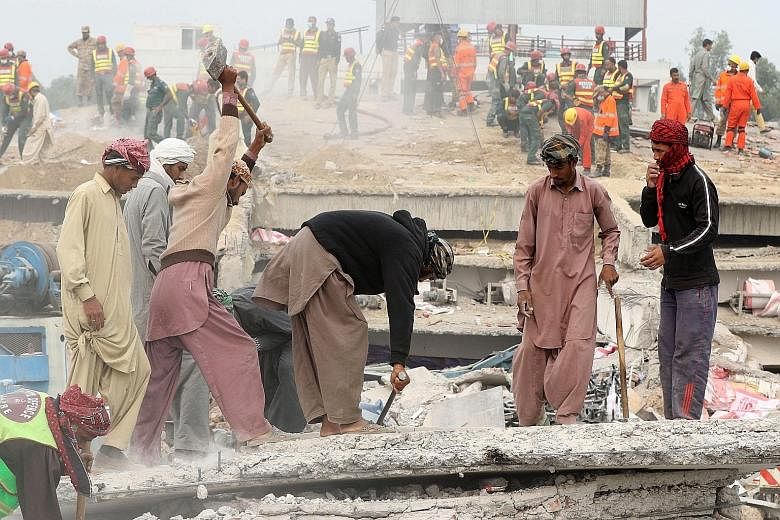 Rescue workers searching for survivors amid the rubble of a factory that collapsed in Lahore, Pakistan, on Friday. At least 23 bodies have been found.