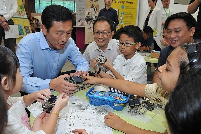 Mr Ong Ye Kung joining children in building small solar cars at the Tinkerama pop-up booth at the Lifelong Learning Festival.