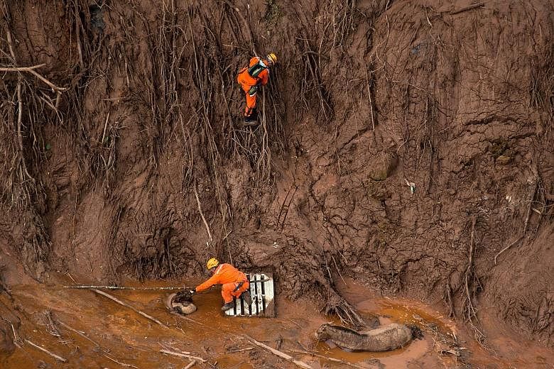 Brazilian firemen rescuing a foal near its mother in the village of Bento Rodrigues last Friday after two tailings dams burst at a nearby mine, unleashing a deluge of thick, red sludge over the village. Below: A car perched awkwardly on top of a hous