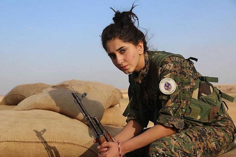 A female fighter for the Syrian Democratic Forces, which include Kurds, Arabs and Syriac Christians, guarding a post outside the town of Al-Hol in north-eastern Syria last week.