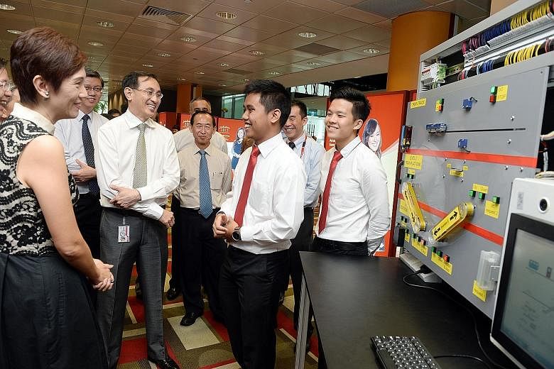Mrs Josephine Teo talking to Singapore Polytechnic students Amirul Husni Sidek (third from right) and Bryan Lim Wen Chong (far right), both 19, during a tour of the school's rapid transport technology programme exhibition. With them is SMRT group chi