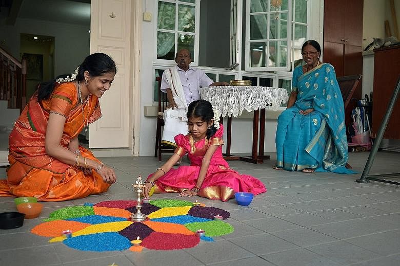 Madam Jayapaul Eswari and her daughter Shree Nethi working on a multi-coloured rangoli floor decoration at the driveway of their Lentor Crescent home yesterday. Behind them are Shree Nethi's grandfather M.K. Narayanan and grandmother Sarasvathi Kasiv