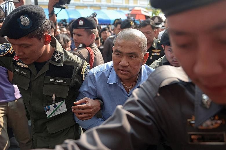 An Oct 21 file photo of Thai fortune teller Suriyan Sucharitpholwong (in blue), 54, also known as Mor Yong, arriving at a military court in Bangkok. The fortune teller, who was charged with royal defamation, died in military custody, officials said y