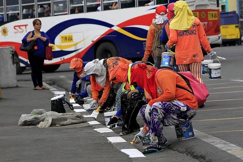 Workers re-painting a pavement in metro Manila as part of a clean-up project for next week's Apec summit in the Philippines.