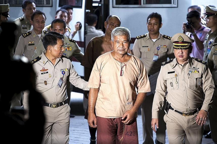 An impassive Manas Kongpan (centre), the most high-profile defendant, being led into court in Bangkok yesterday.