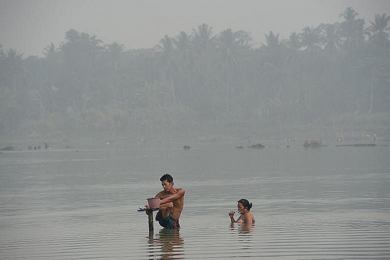 Villagers bathing in a river shrouded in haze in Sumatra last month. Scientists say they have found harmful gases in the air in Indonesia's Central Kalimantan, including ozone, carbon monoxide, cyanide, ammonia, formaldehyde, nitric oxide and methane