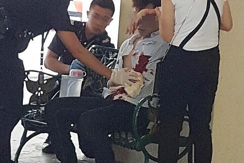 Policemen attending to the victim as the attacker's wife helps them after a stabbing incident at Woodlands Avenue 6.