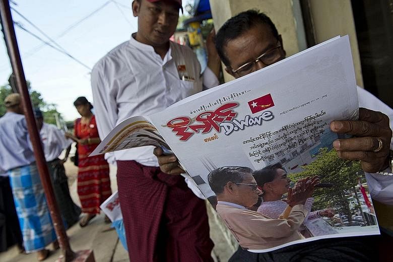 Myanmar residents reading a newspaper with a picture of opposition leader Aung San Suu Kyi and National League for Democracy party chairman Tin Oo outside the NLD headquarters in Yangon. Analysts believe the party is headed for a solid mandate to for