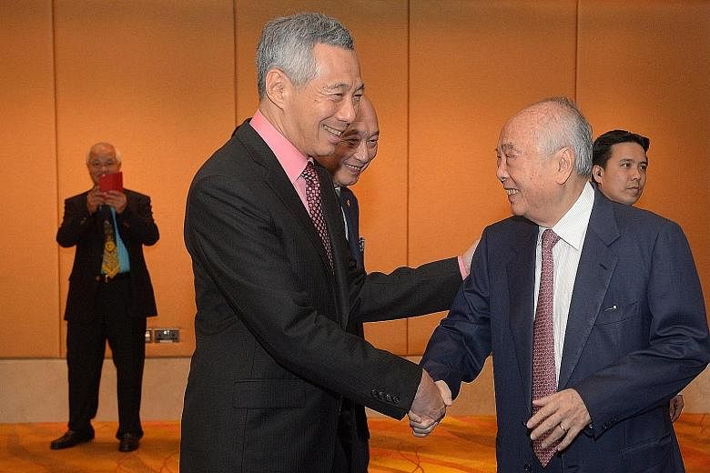 Prime Minister Lee Hsien Loong exchanging greetings with UOB chairman emeritus and adviser Wee Cho Yaw at the bank's 80th anniversary dinner, as UOB chief executive Wee Ee Cheong looks on.