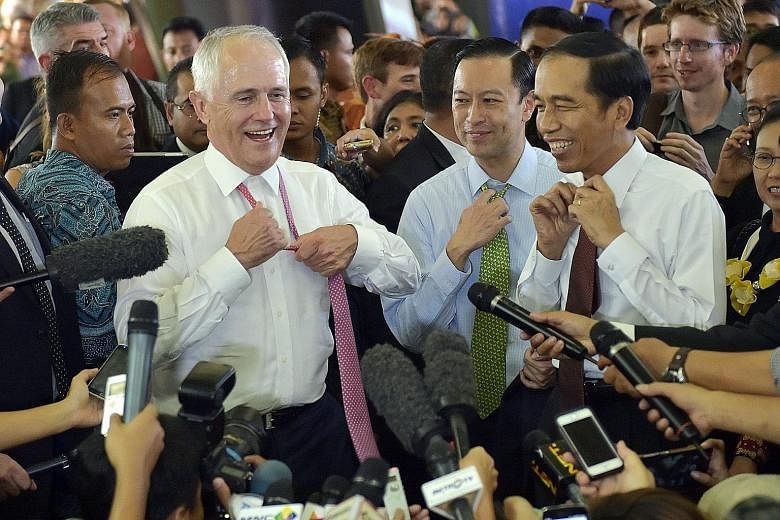 Australian Prime Minister Malcolm Turnbull and Indonesian President Joko Widodo shedding their neckties during a walkabout at Jakarta's Tanah Abang market yesterday. Mr Turnbull is said to be the first foreign head of state invited by Mr Joko to go o