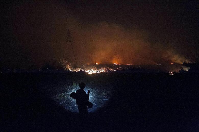 A resident with a flashlight watching as a fire burned on peatland in Central Kalimantan this month. During local elections season, there is a higher possibility of land parcels, handed out as campaign incentives by errant regional leaders, being cle