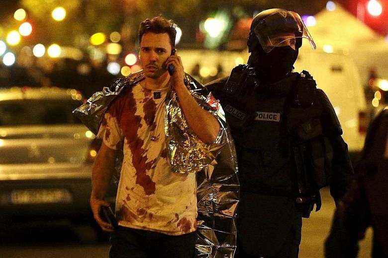 A French policeman assisting a blood-covered victim near the Bataclan concert hall following the attacks in Paris on Friday. France remains under a nationwide state of emergency.