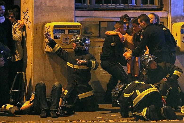 French fire brigade members helping an injured victim near the Bataclan theatre following shootings in Paris on Friday.