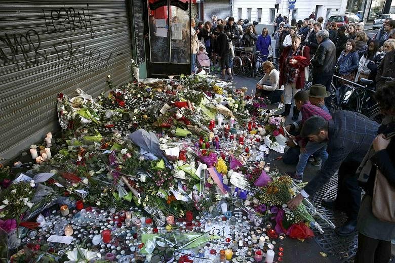 People paying their respects at one of the attack sites in Paris yesterday. The violence claimed 129 lives and injured 352, including 99 in a serious condition.