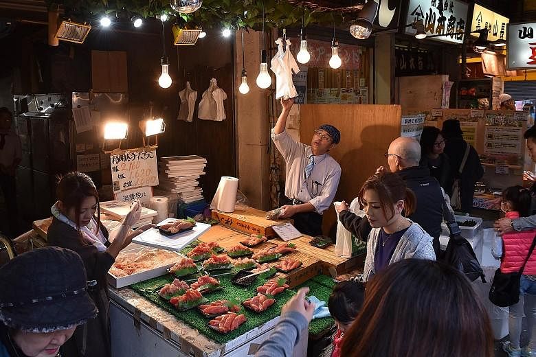 Customers at a seafood shop in Tokyo. Japan's Cabinet Office yesterday said GDP shrank 0.2 per cent in the July-September period, or an annualised contraction of 0.8 per cent, marking the second straight quarterly decline - considered a technical rec