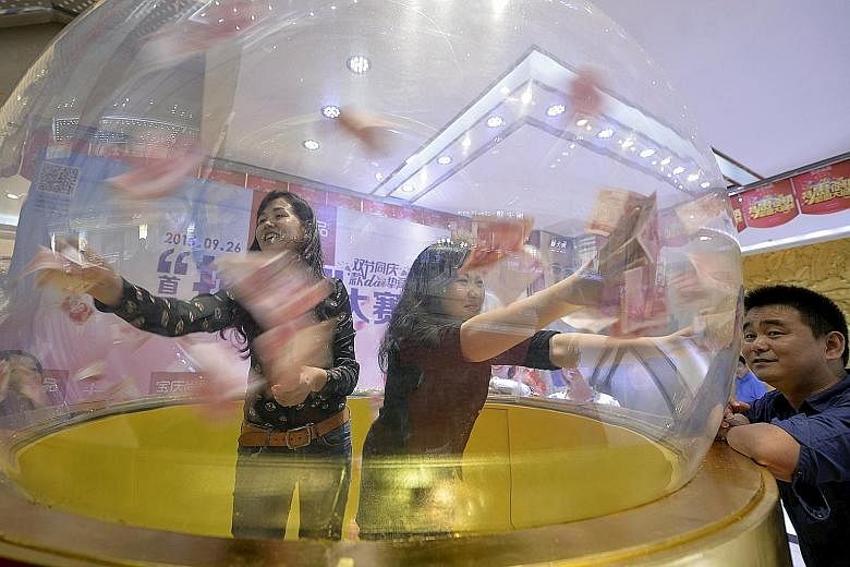 Participants trying to catch 100-yuan notes flying inside a dome at a jewellery store's promotional event in Nanjing, Jiangsu province, on Sept 23. Since China surprised world markets by devaluing its currency around 2 per cent in August, net capital