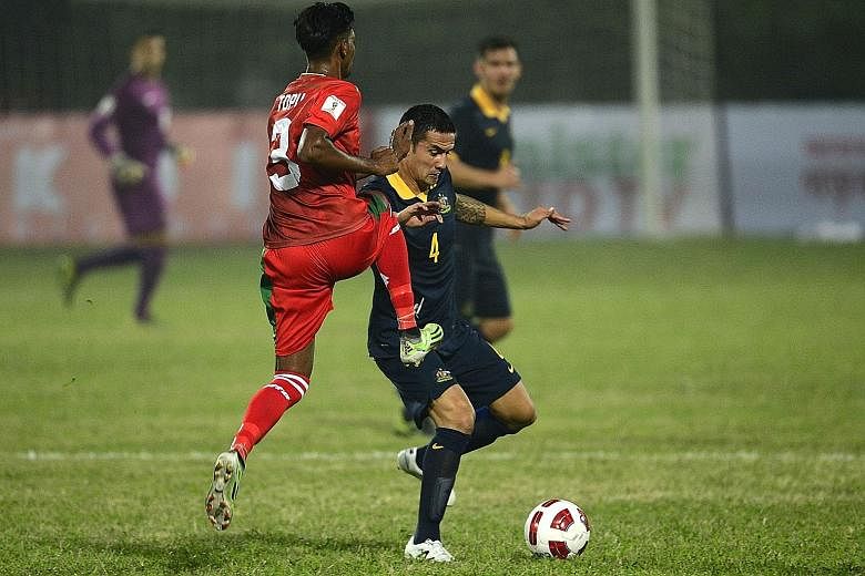 Australia's Tim Cahill (right) vying for the ball with Bangladesh's Topu Barman during their Asian Group B World Cup qualifier in Dhaka yesterday. The veteran forward scored his second international hat-trick as Australia set aside security worries t