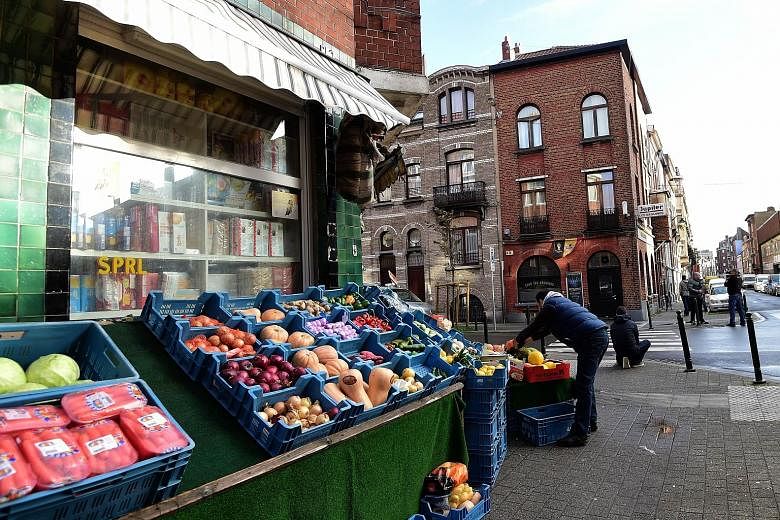 A shopkeeper setting up his wares in Brussels' Molenbeek district yesterday, across the road from the Cafe Les Beguines owned by Ibrahim Abdeslam, one of the suicide bombers implicated in the Paris attacks. In some parts of Molenbeek, where the Paris