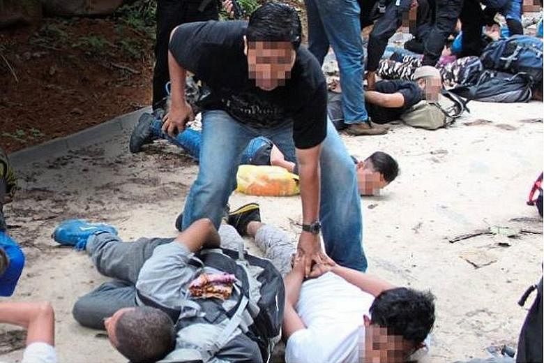 Officers from Malaysia's Bukit Aman Special Branch Counter Terrorism Division detaining suspects at the foothills of Hutan Lipur Gunung Nuang in April. The men, suspected ISIS militants, were testing bombs at the foothills of the mountain when they w