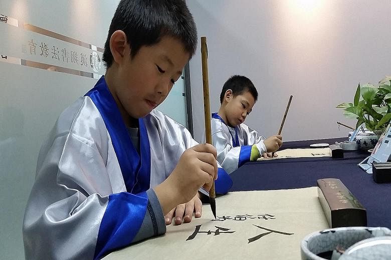 Ren Bowei, seven (left), and Ji Zhengpeng, eight, practising calligraphy at Hanxiang calligraphy school. Hanxiang, like many other guoxue centres, infuses its classes with Confucian teaching.