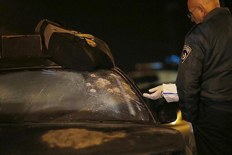 Israeli policemen inspecting bullet holes on the windscreen of a Palestinian attacker's car at the scene of an attack close to the West Bank Jewish settlement of Alon Shvut on Thursday.