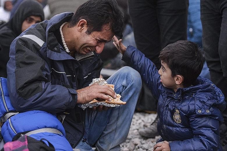 A boy consoling his father at the border between Greece and Macedonia. Macedonia started granting passage only to refugees from war-affected nations like Syria, Iraq and Afghanistan yesterday.