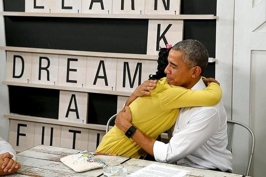 US President Barack Obama receiving a hug from a refugee (left) and greeting a student (right) while touring the Dignity for Children Foundation - which runs classes for poor children, including refugees - in Kuala Lumpur yesterday. Mr Obama has vowe