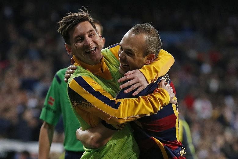 Lionel Messi (left) embracing Andres Iniesta after the latter had scored the third goal for Barcelona against Real Madrid on Saturday. Messi, who started on the bench, set up the last goal of the emphatic 4-0 victory.