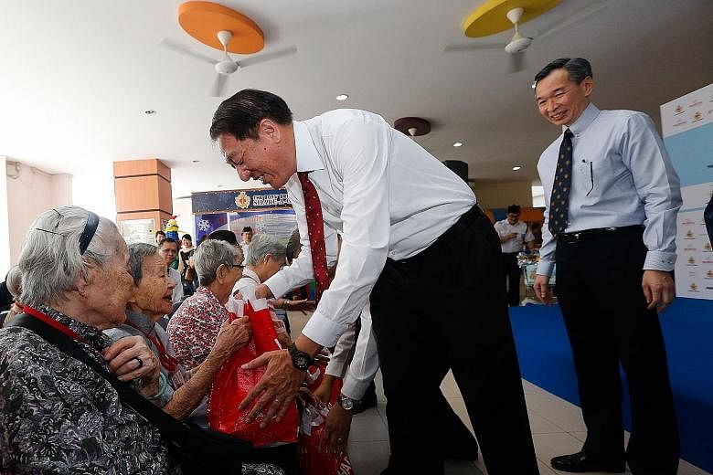 Deputy Prime Minister Teo Chee Hean presenting food hampers to beneficiaries from Kheng Chiu Happy Lodge yesterday. He is accompanied by Mr Lui Chong Chee, the organising committee chairman of the Boys' Brigade's Share-a-Gift project. Mr Lui said tha