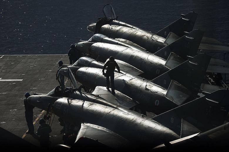 French navy personnel working on warplanes. Russia said its strikes had destroyed facilities near ISIS' stronghold of Raqqa, which is also the target of French air strikes.