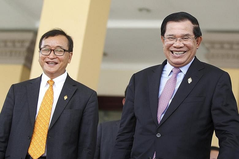 Mr Sam Rainsy (far left), Cambodia's most prominent opposition leader, and Prime Minister Hun Sen in less fraught times. An arrest warrant has been issued for Mr Sam Rainsy after his verbal spat with the strongman Premier.