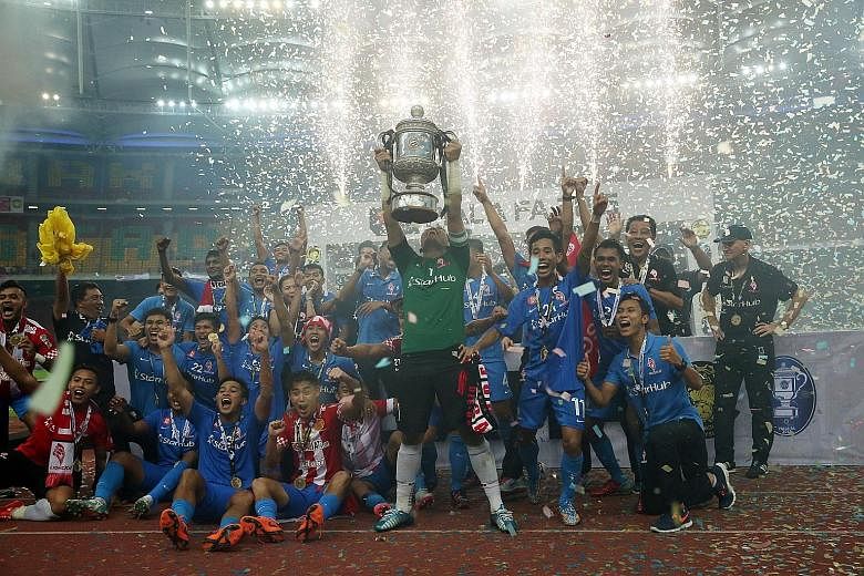 LionsXII goalkeeper Izwan Mahbud lifting the Malaysian FA Cup trophy as the team celebrated its victory over Kelantan in Kuala Lumpur's Bukit Jalil National Stadium in May. Players have been left scrambling for fresh contracts after the FAM's decisio